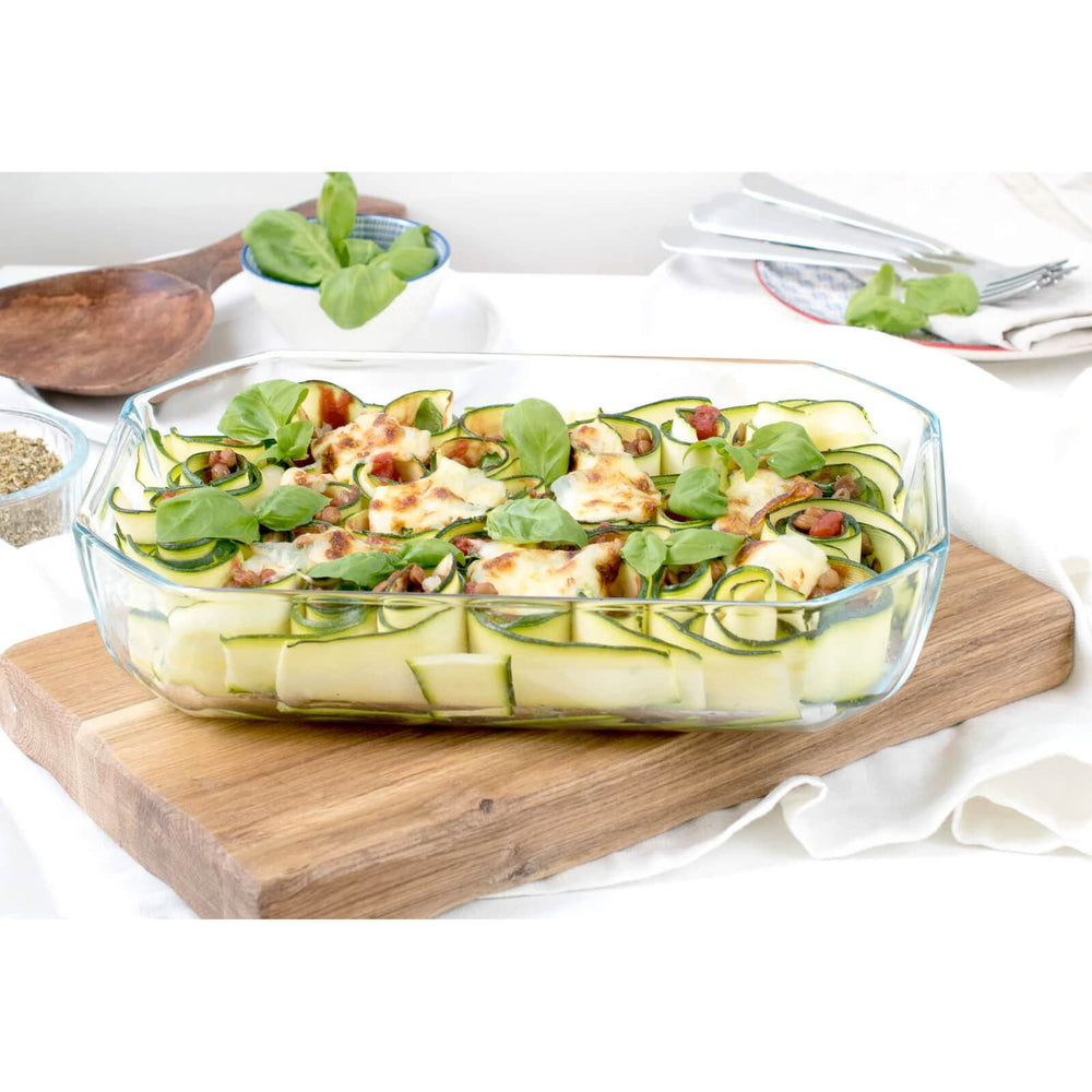 Glass roasting dish with vegetable noodle salad on a wooden board