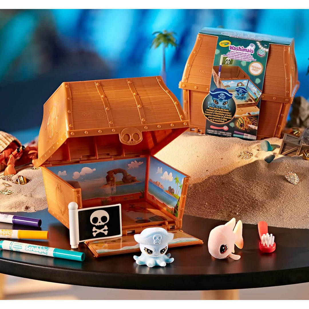 Scrubbie pets toy pirate chest with figurines and markers on a table with a beach-themed background
