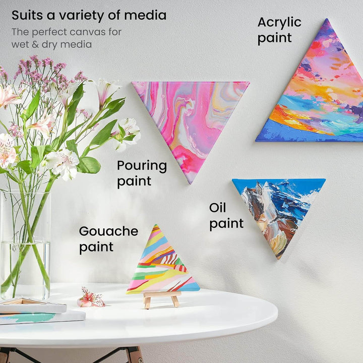 Triangle shaped artist canvases for a variety of media, painted and hanging on a wall with table and flowers