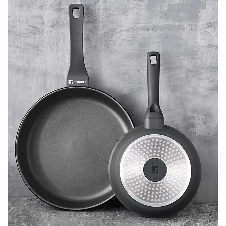 2 different size black retro frying pans, one showing a dot induction base