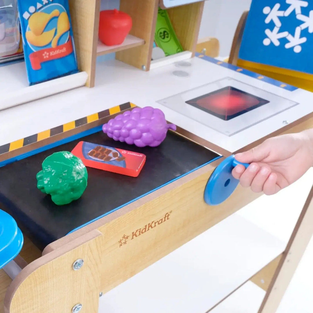 Child turning handle to move conveyor belt with pretend shopping on it