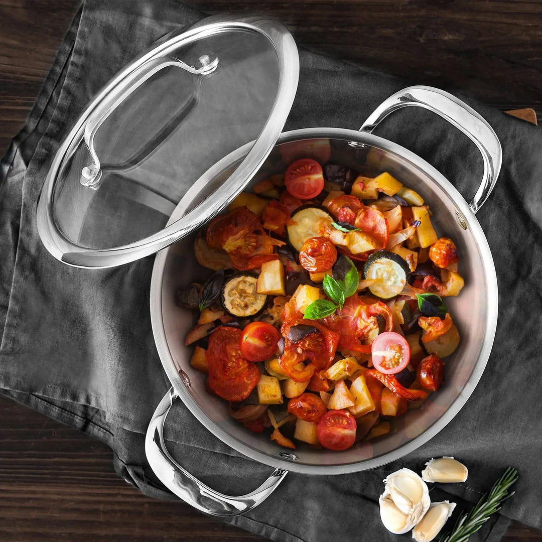 Overhead view of a casserole dish with glass lid off to show a vegetable stew with tomatoes garlic and herbs