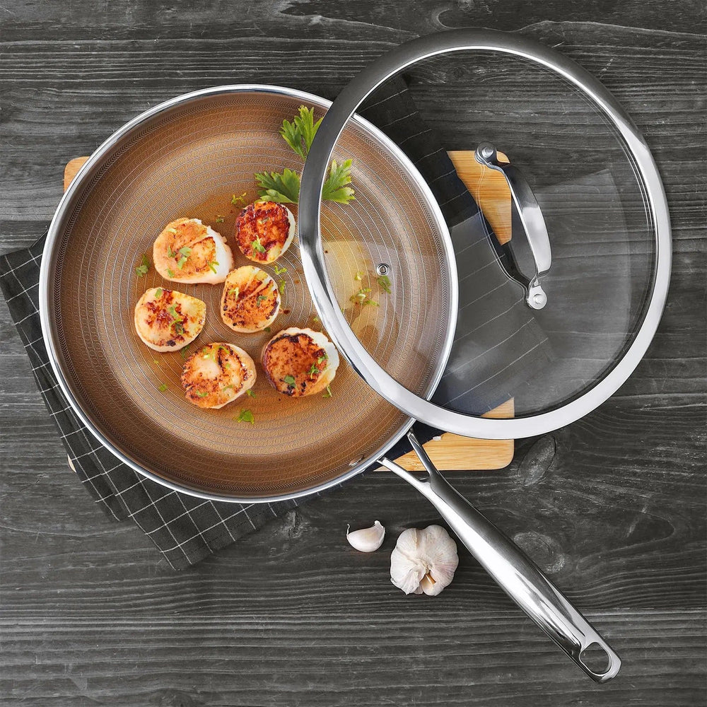 Gold frying pan with lid set aside to show fried scallops, on a dark grey wooden table