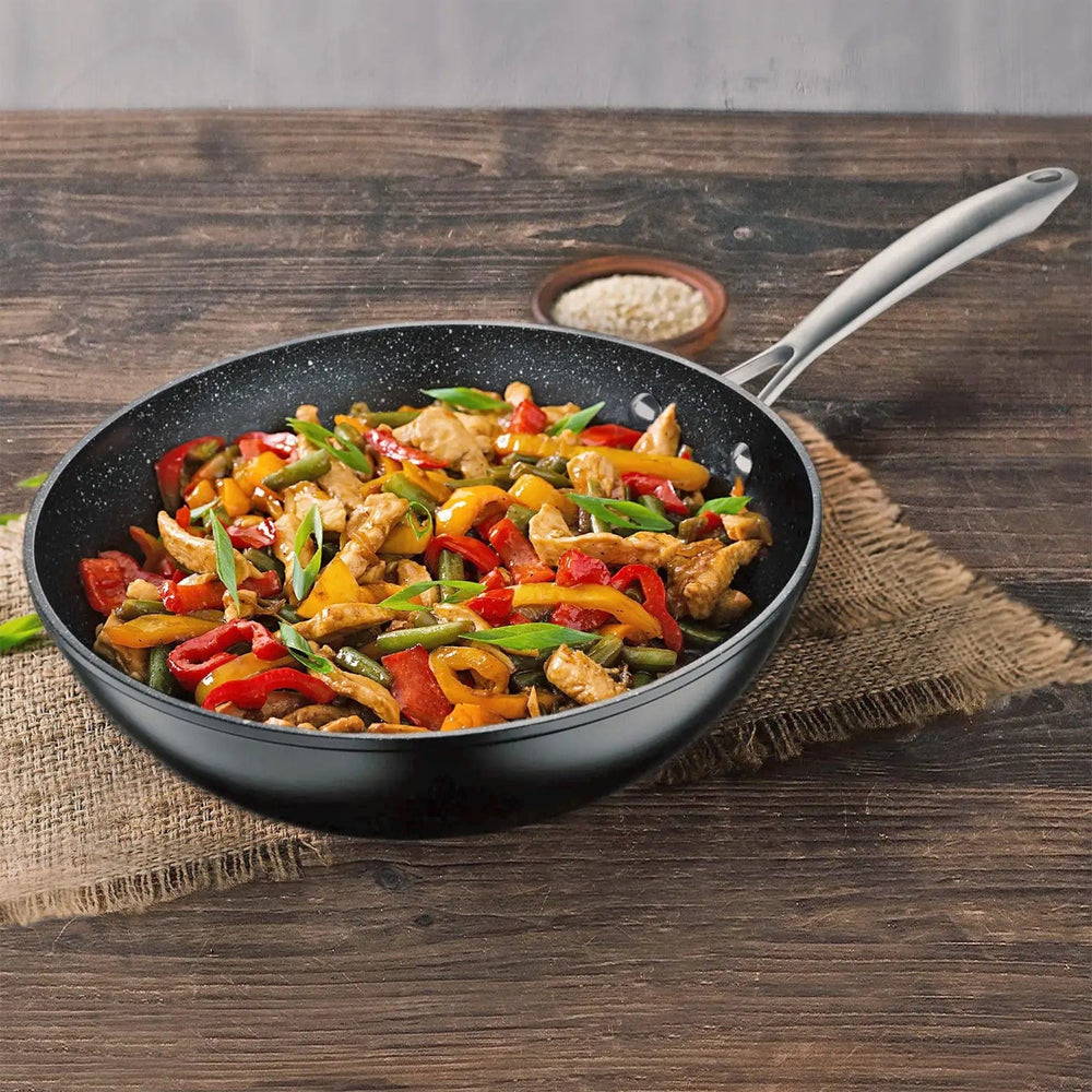 Black marble coated Wok with cooked stir fry food on a wooden worktop with hessian place mat