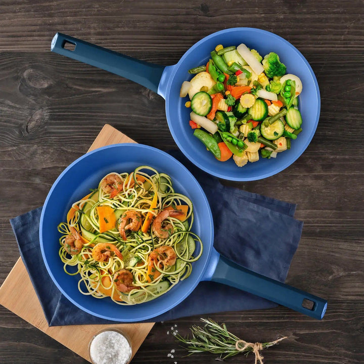 Set of 2 Blue Gastro Diamond frying pans with filled stir fry food, served on a wooden table