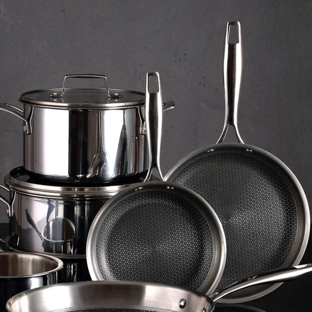 Black and silver frying pans, stock pots in front of a black wall