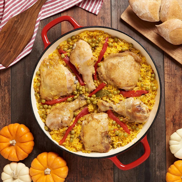 Overhead view of a table with coloured gourds and a red casserole dish filled with chicken and rice