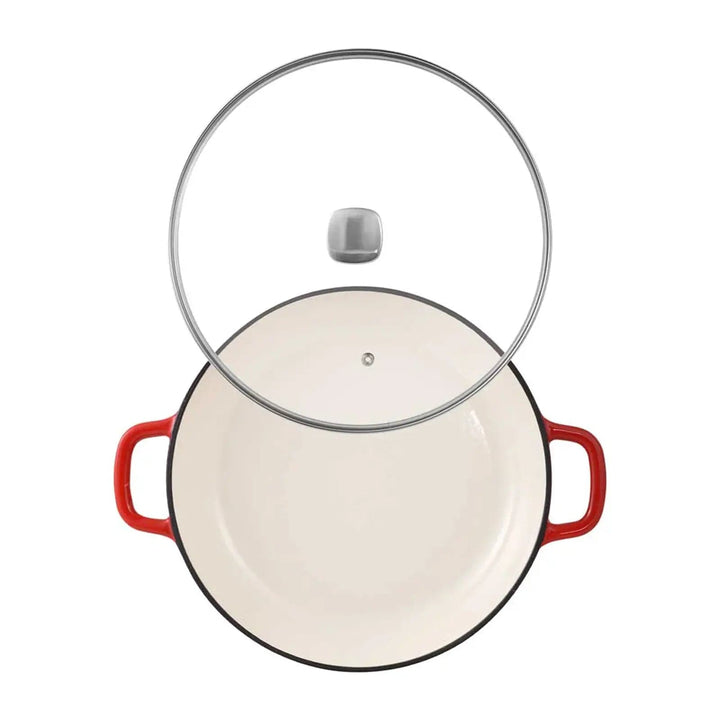 Top view of a red casserole dish with cream enamel interior and a glass lid with silver handle