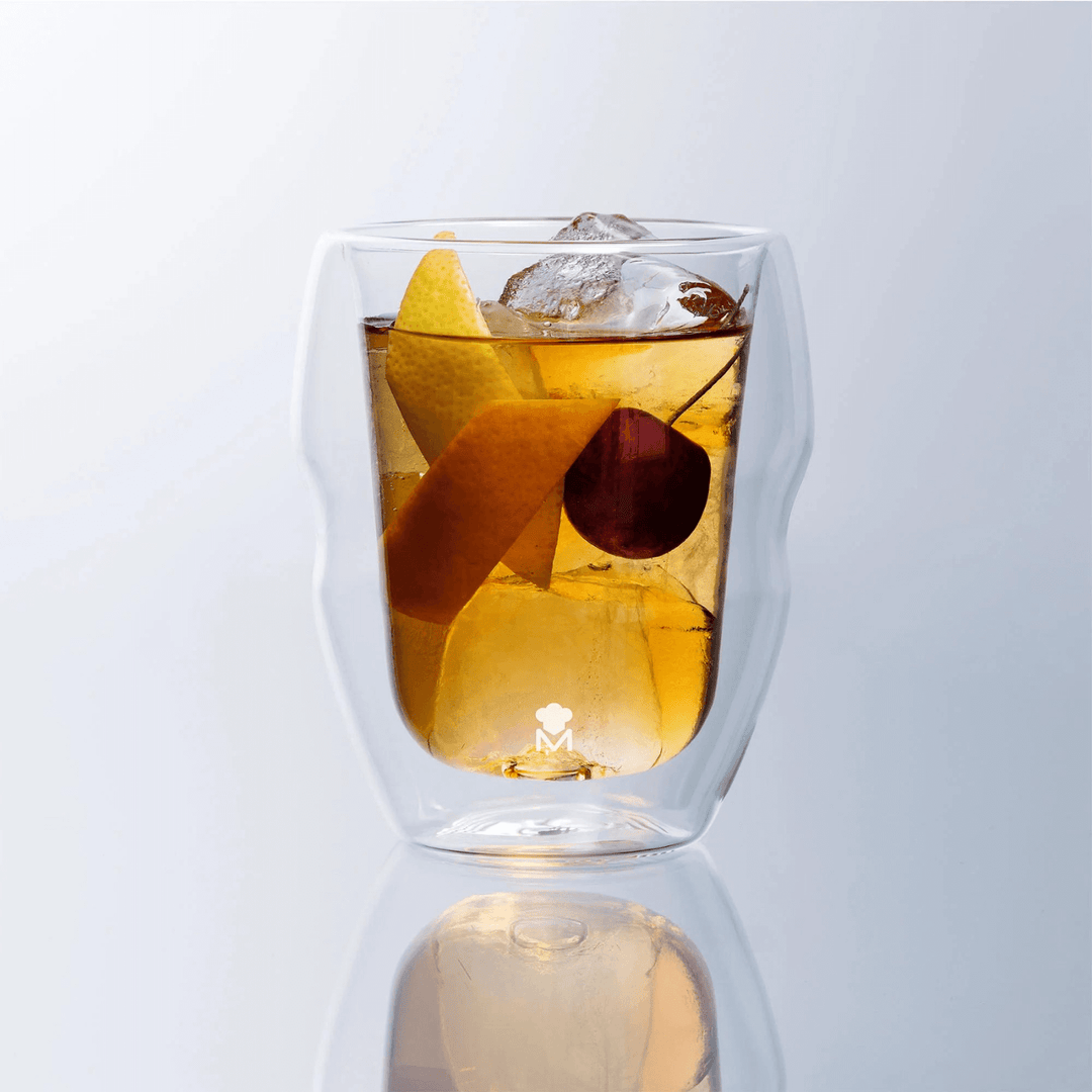 rock glass tumbler featuring orange liquid beverage with lemon, ice and a cherry