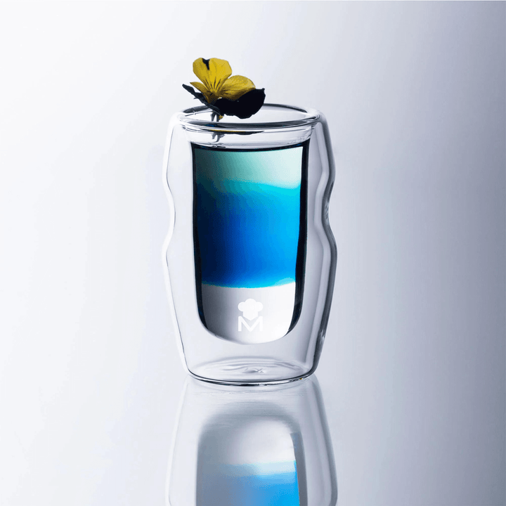 double wall glass featuring blue liquid inside with flower placed on top