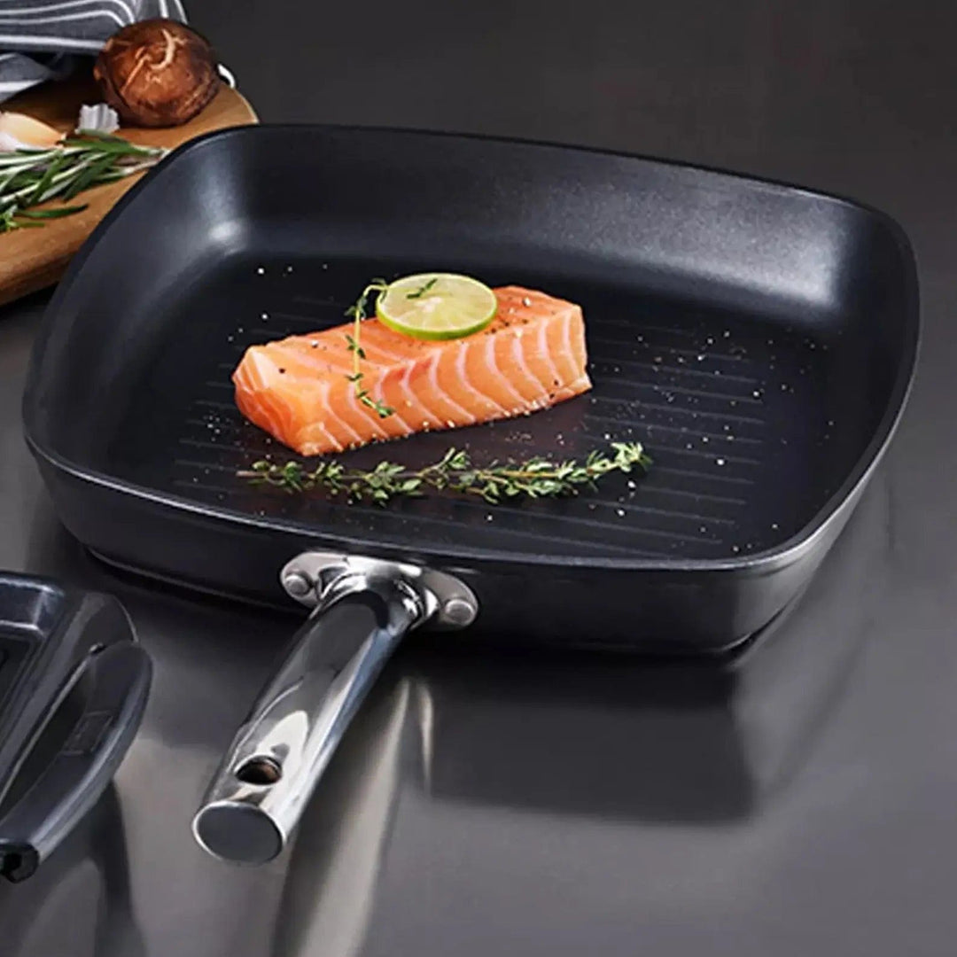 Grill pan with slice of salmon, lime and herbs