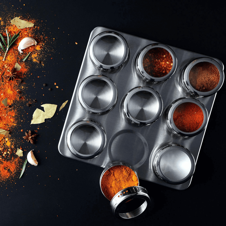 spice rack set filled with colourful spices on blaxk worktop with stylised ingredients