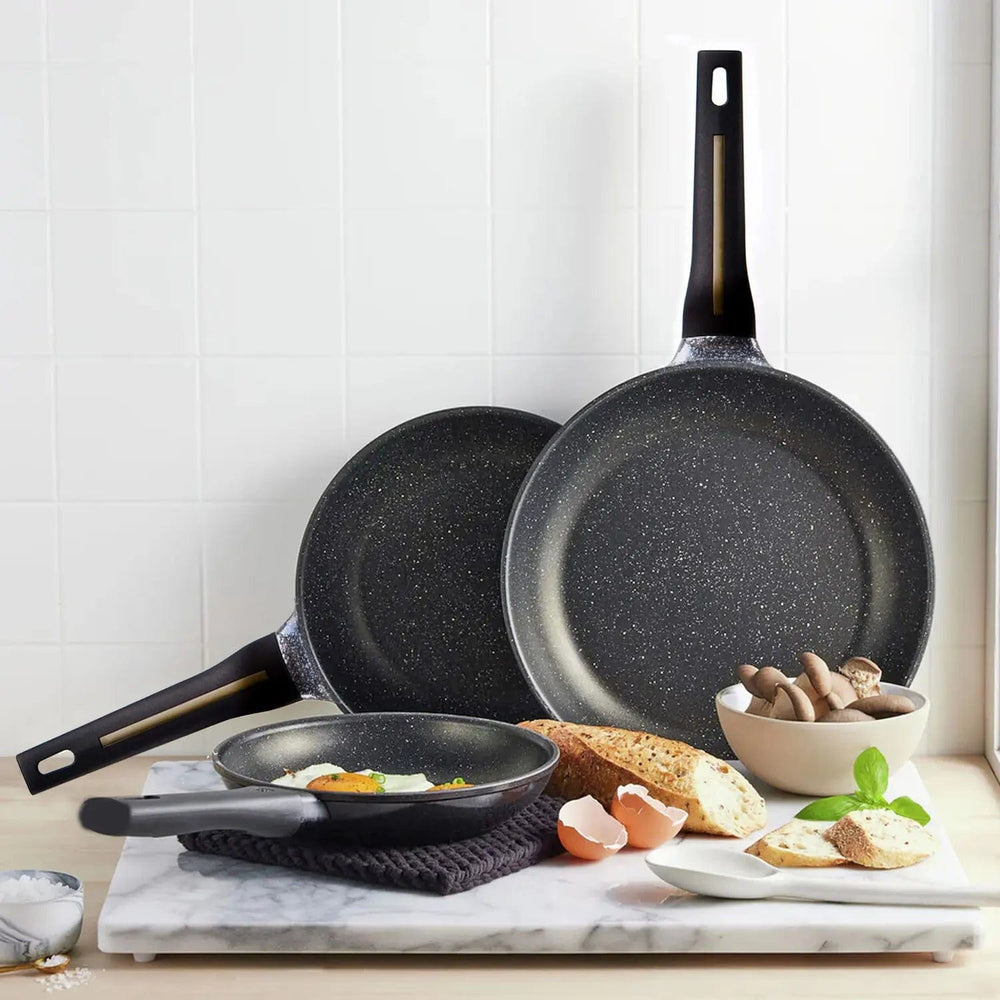 Bistro black frying pans on a worktop with marble chopping board, bread and fried egg