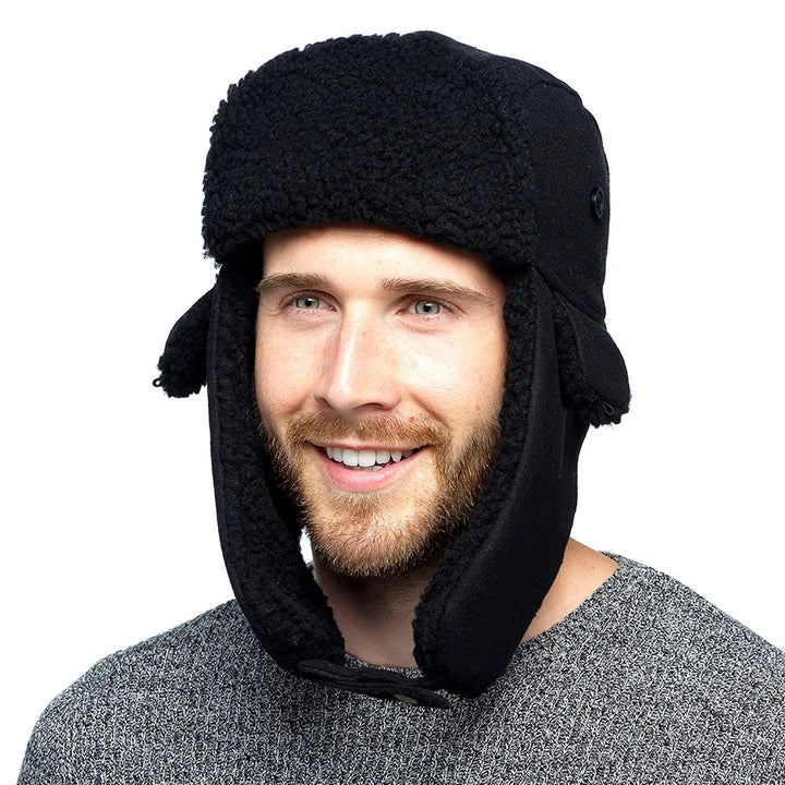 man wearing a black fleece trapper hat with long ear flaps fastened under the chin