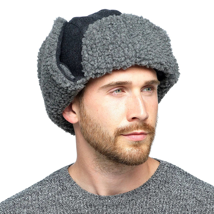 man wearing a grey fleece trapper hat with long ear flaps fastened on top of the winter hat