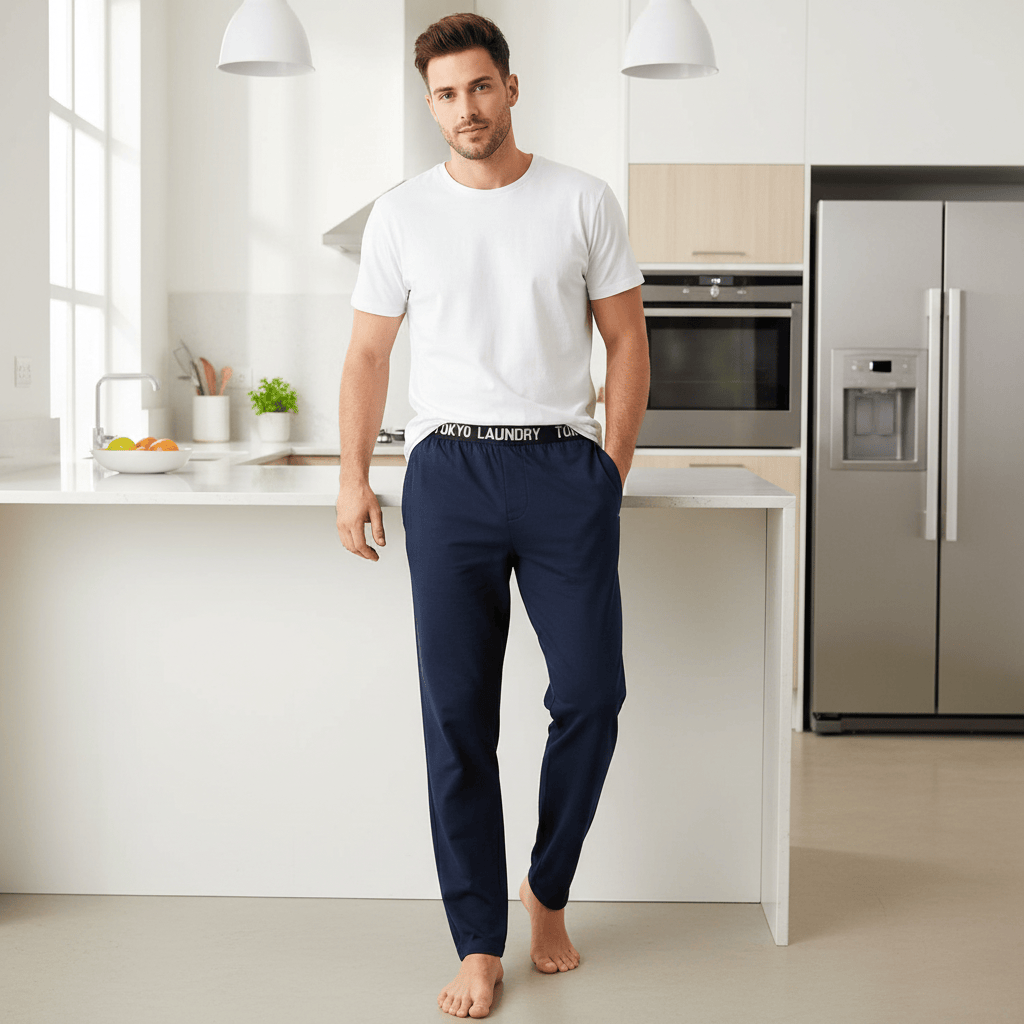 Man wearing navy blue pants with 'Laundry' text in a modern kitchen.