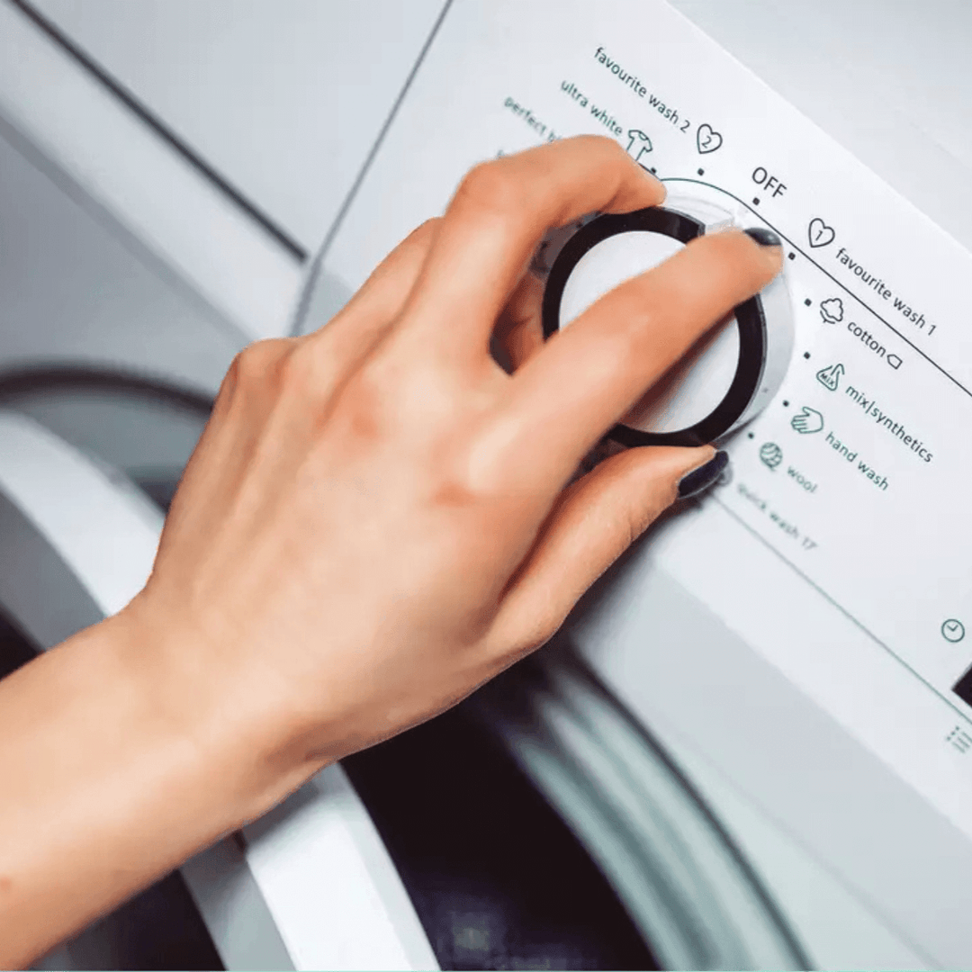 Hand adjusting settings on a washing machine 