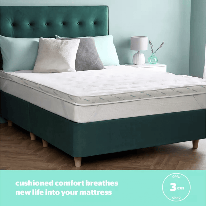 Mattress with green headboard and white bedding in a bedroom setting