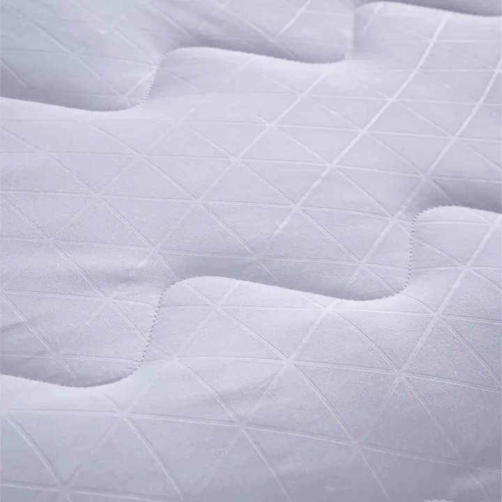 Close-up of a quilted white mattress pad with diamond pattern