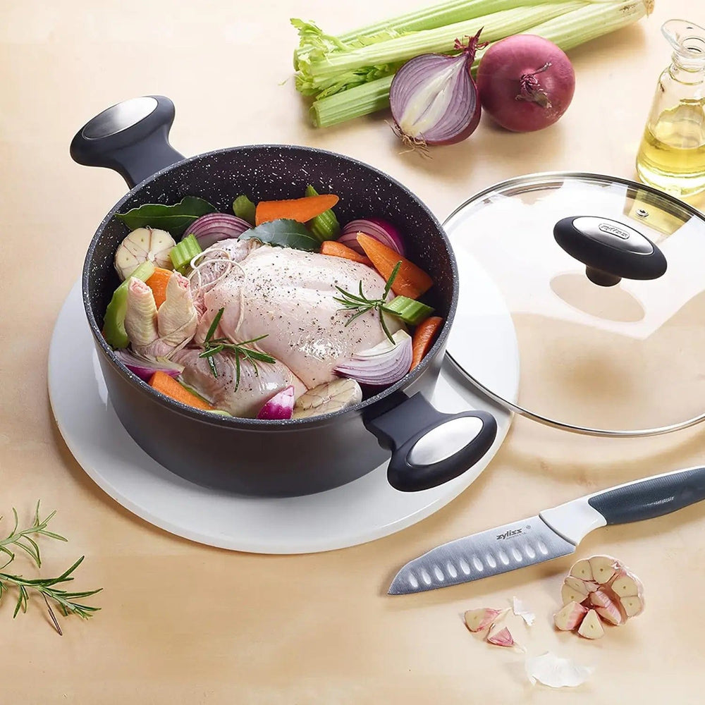 Large handled, Stock pot filled with chicken and vegetables on a tbale with knife and glass lid