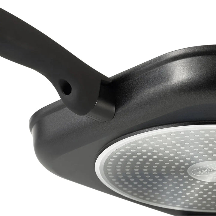 Silver circular base of black grill pan with even heat distribution