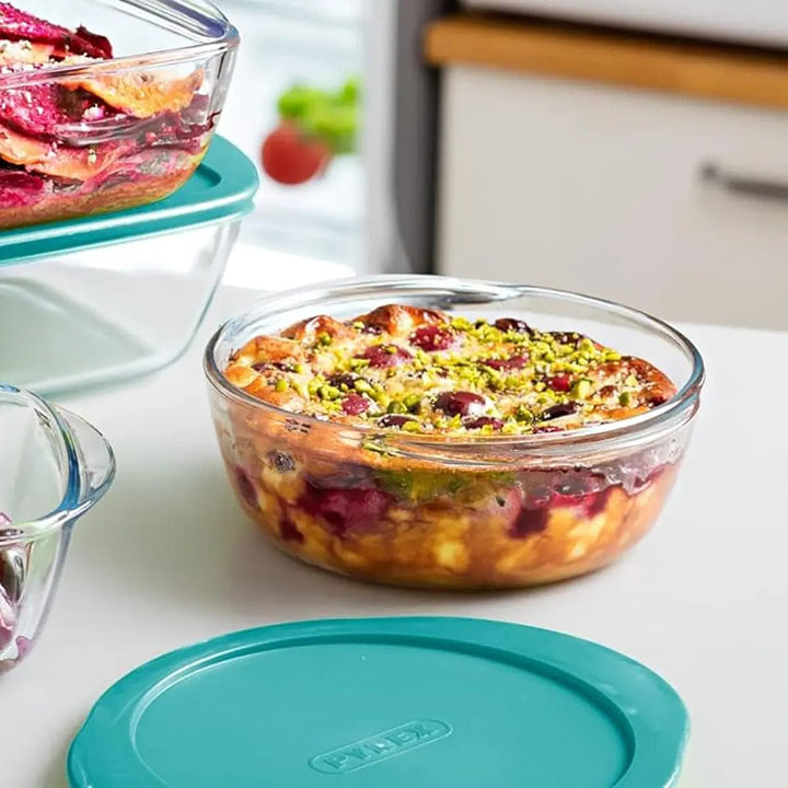 Round glass oven dish filled with Mediterranean casserole, with lid sitting on a table in a kitchen