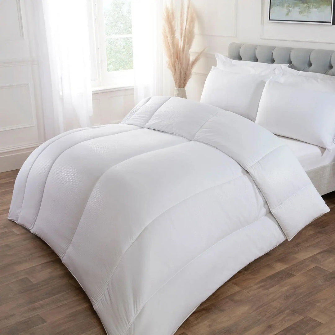 Large segmented quilt on a double bed in a bedroom with neutral colours