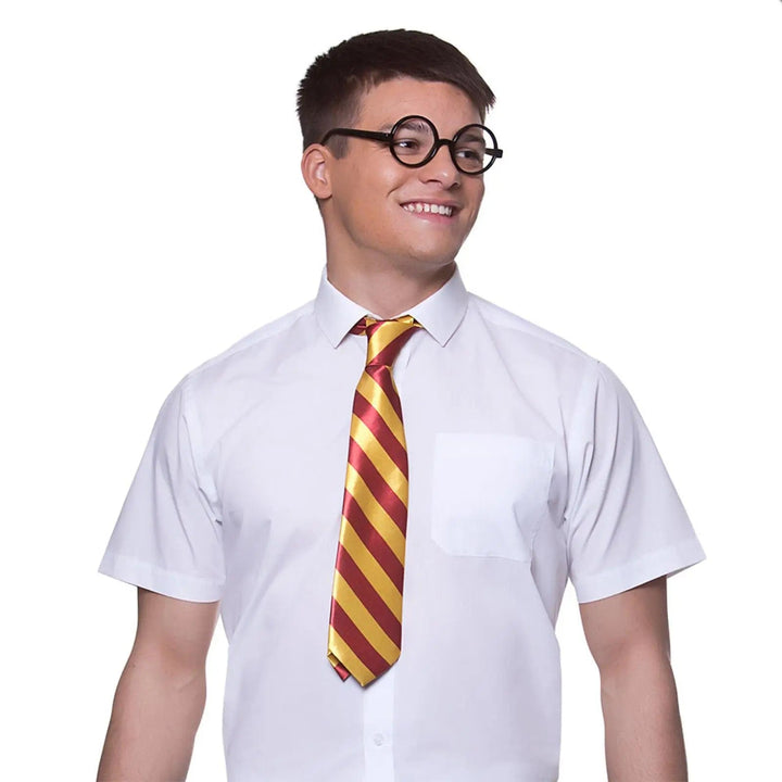 Young man wearing a gold and red tie, white shirt and a pair of thick black rimmed glasses for Harry Wizard fancy dress costumes