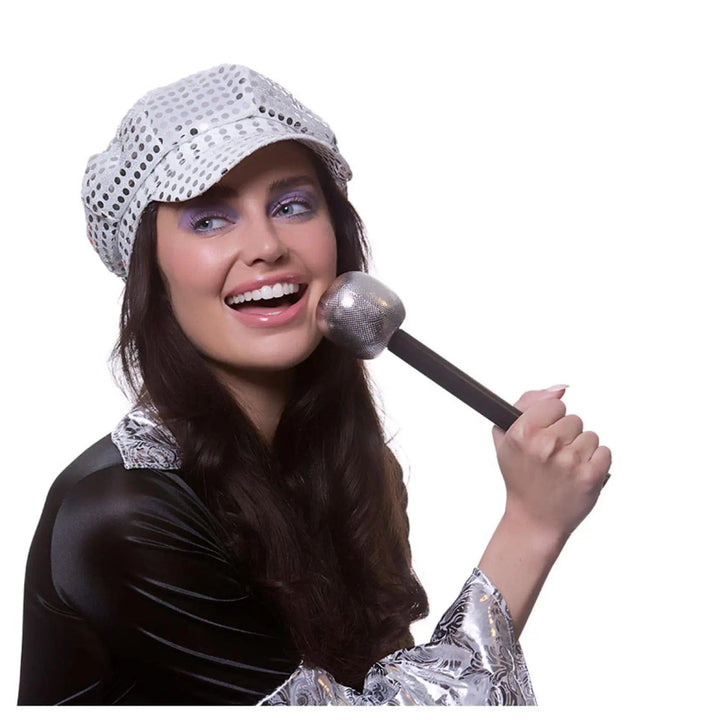 Lady wearing a 60s pop star costume holding a black and silver large microphone 