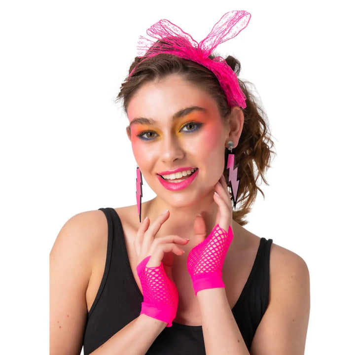 Lady dress up in 1980s fancy dress neon pink hair bow, lightning shape earrings and fingerless net gloves