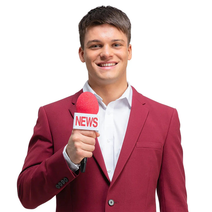 Man dressed in a burgundy jacket holding a bright red NEWS microphone for fancy dress parties