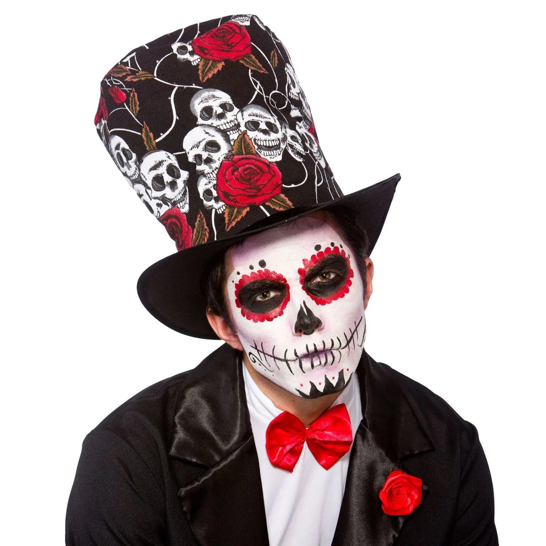 Man dressed up for Day of the Dead festival with large skull and roses top hat, red bow tie and red rose