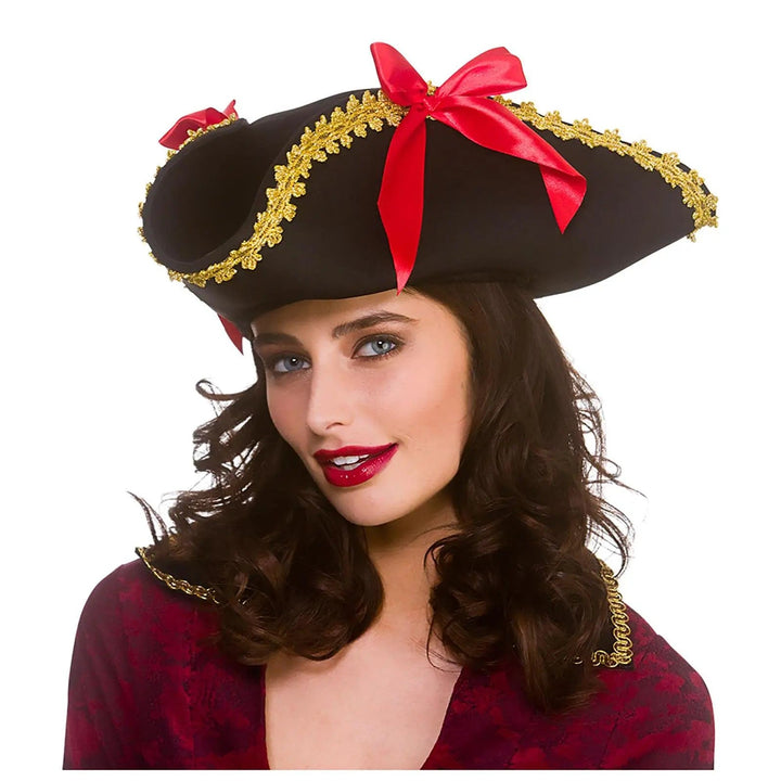 Woman wearing a black pirate hat with gold braid trim and red ribbon bows for fancy dress costumes