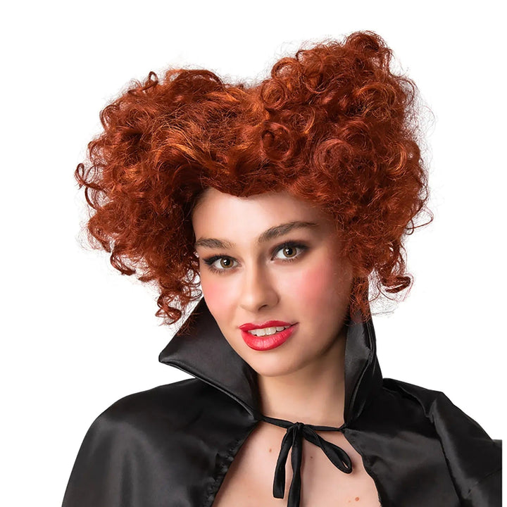 Female model wearing a red queen of hearts wig with curly hair shaped like a heart, and wearing a black cape tied at the collar