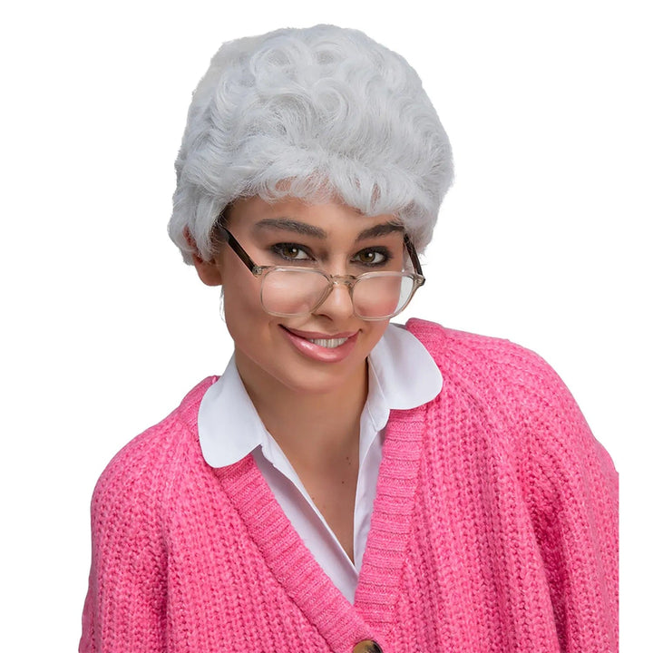 Lady wearing a grey permed wig and pink cardigan for old lady fancy dress costume