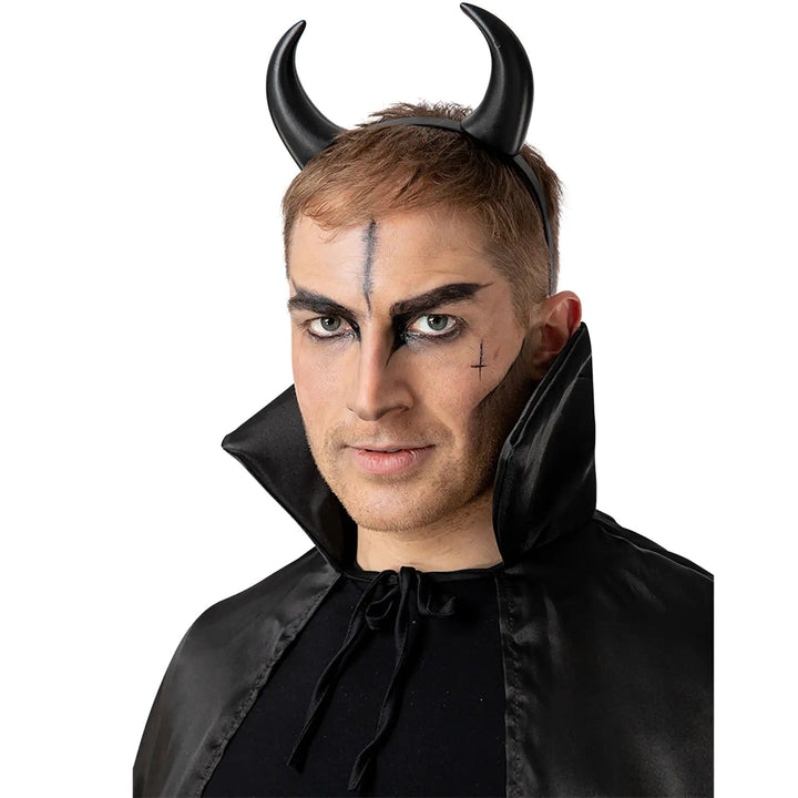 Man wearing a set of black devil horns and high collar cape for fancy dress Halloween parties