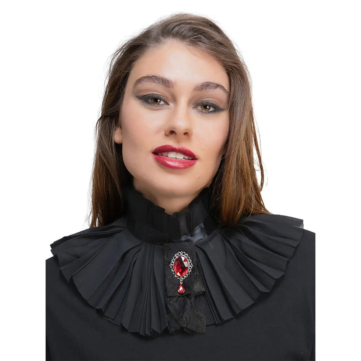 Woman wearing a black pleated neck collar with black lace and large red gemstone brooch