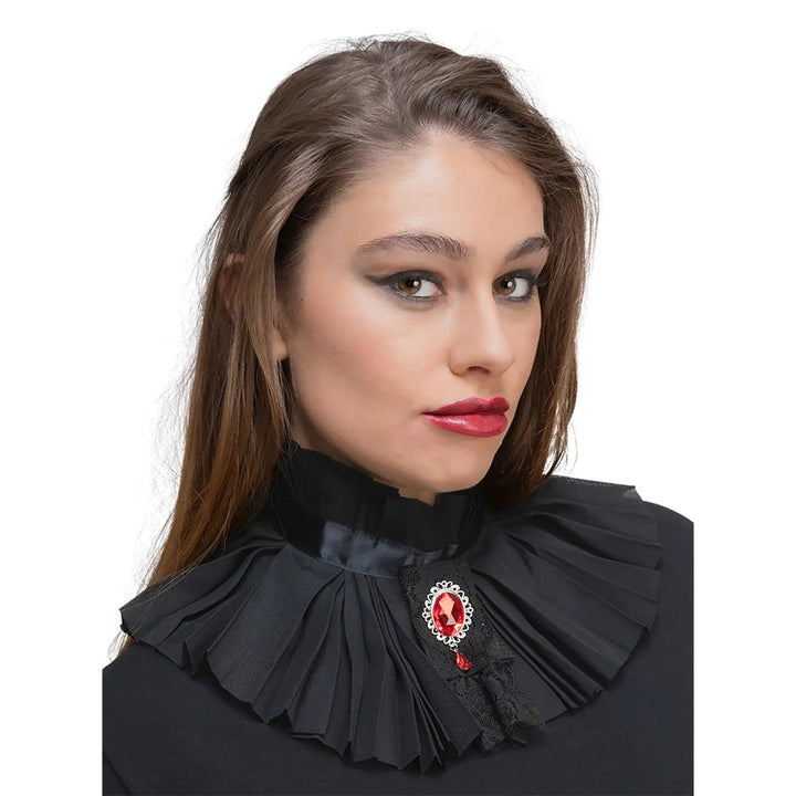 Model wearing a black pleated neck collar with black lace and large red gemstone brooch