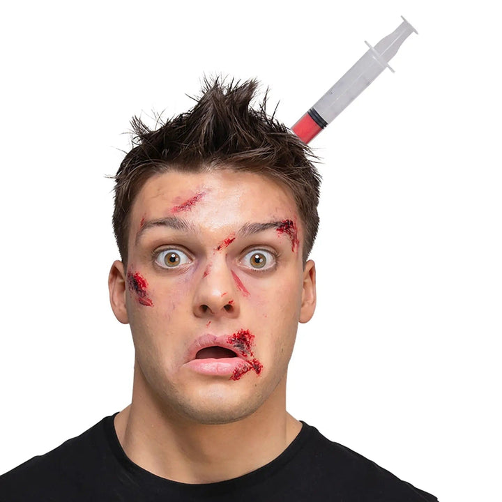 Man with horror make up and a plastic syringe head piece for Halloween fancy dress costumes