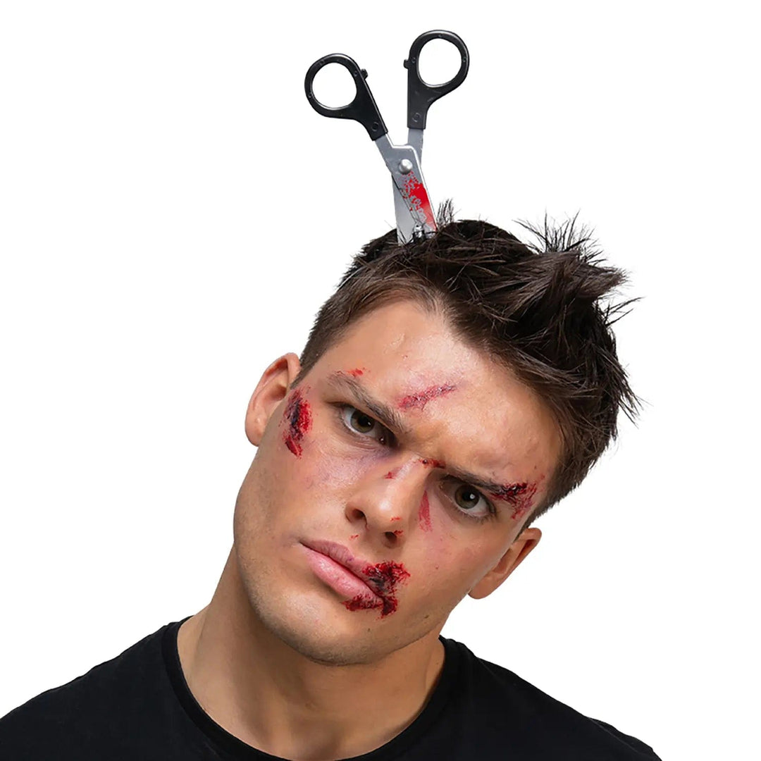 Man with bloody makeup and a pair of scissors Halloween prop on his head