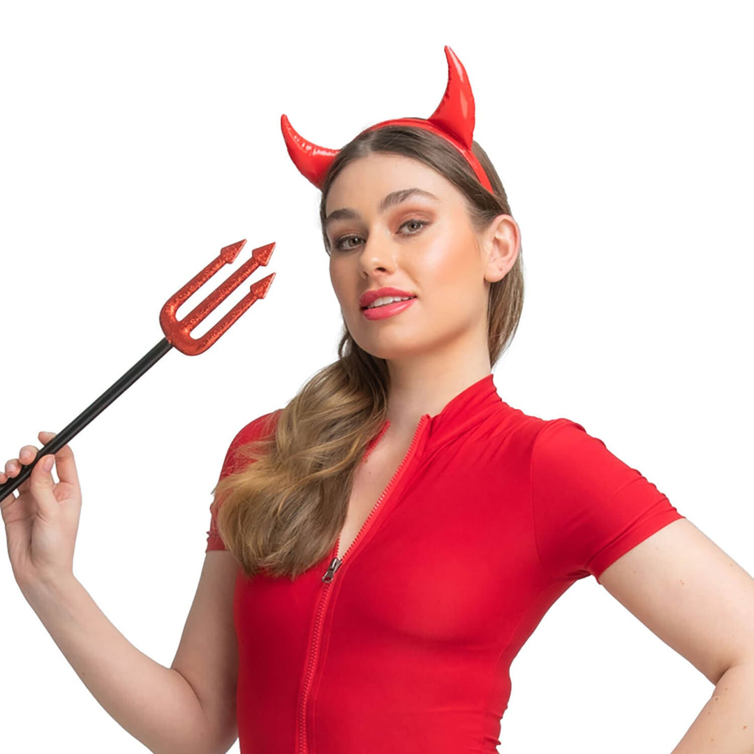 Woman wearing a red outfit with devil horns and holding a trident on a white background