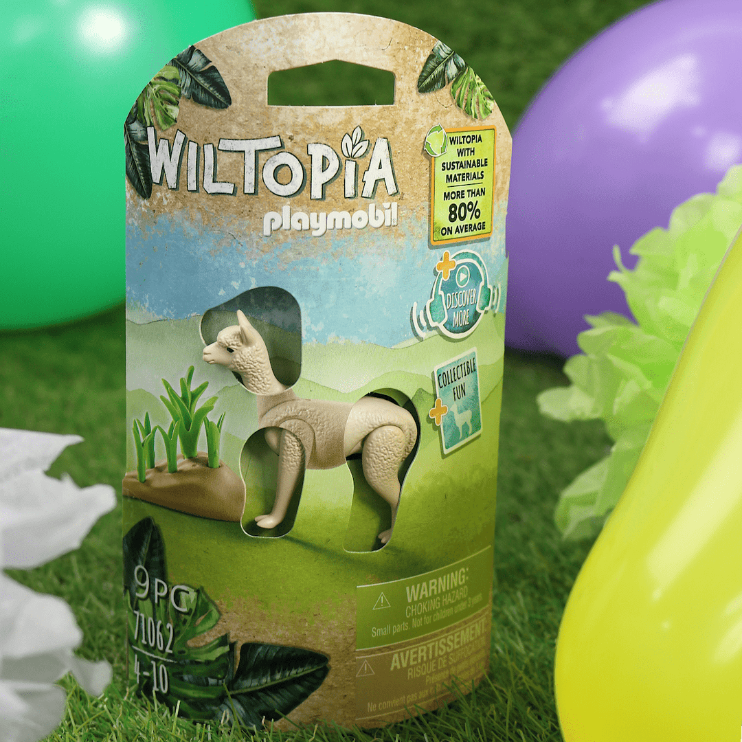 wiltopia alpaca package on grass with colourful balloons and decorations in the background