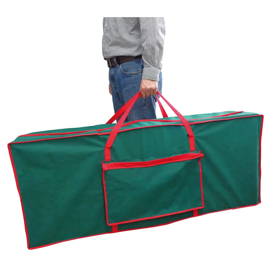 Man carrying a green and red Christmas tree storage bag with side pocket