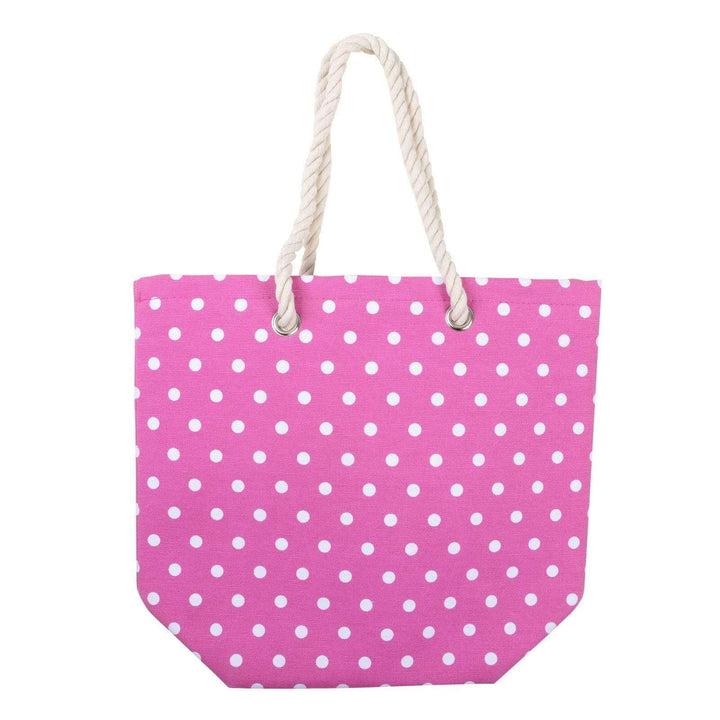 Pink beach bag with white polka dots and a rope handle on a white background