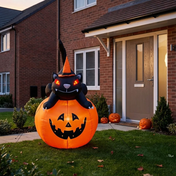 An inflatable Halloween decoration featuring a black cat wearing an orange witch hat sitting on a large orange jack-o&