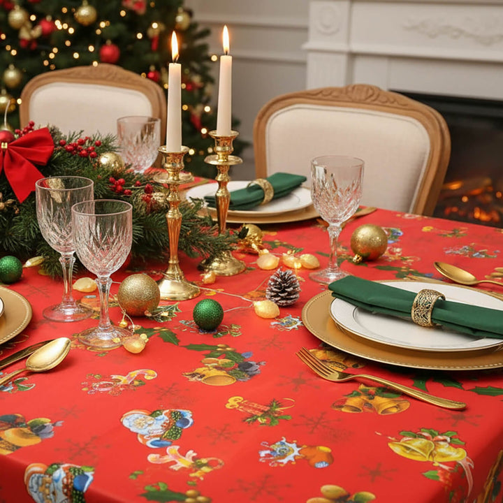 Christmas dinner table set with a red tablecloth with gold bells wine glasses and gold cutlery
