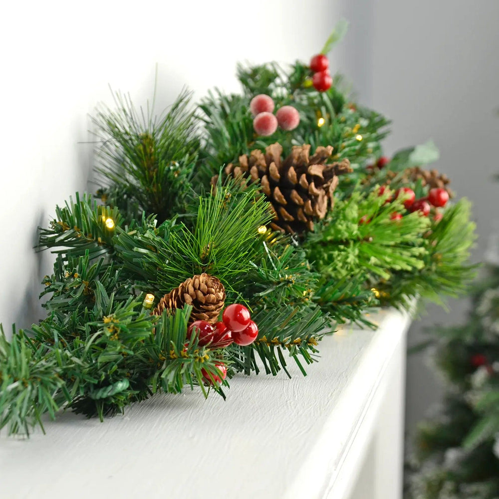 Traditional green foliage Christmas swag with white LED lights, pine cones abd red berries on a mantlepiece