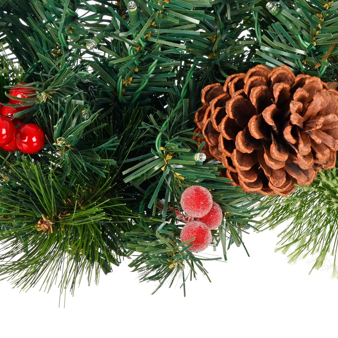 Detail of frosted red berries, a pine cone and green pine branches on a Christmas light up swag decoration