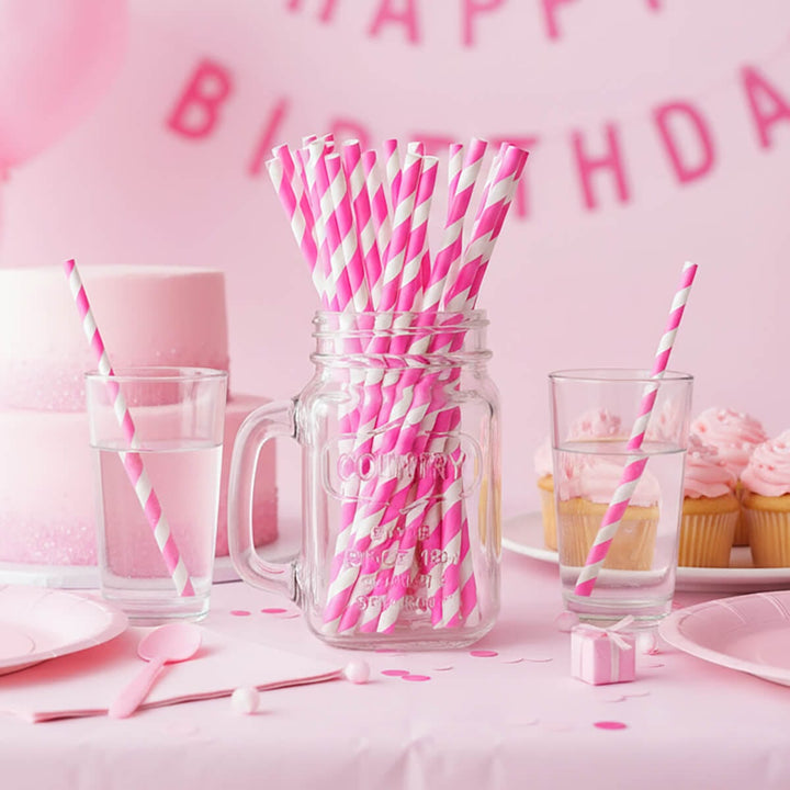 Glass jar full of pink and white straws on a pink theme birthday party table