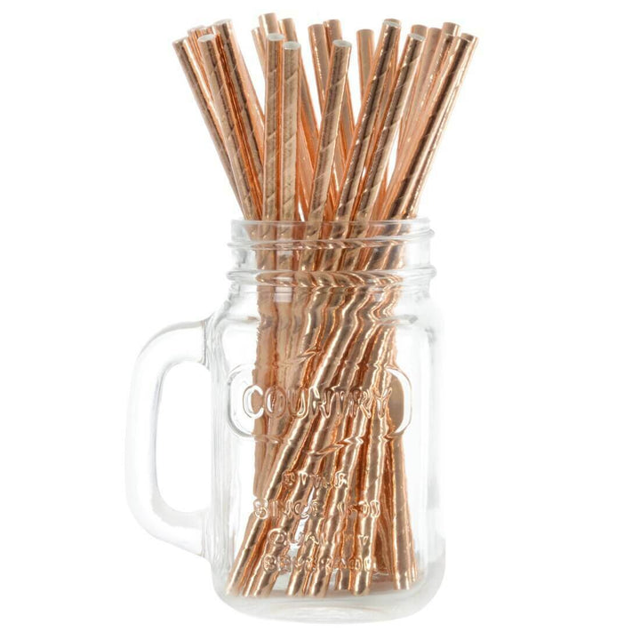 Rose gold drinking straws in a glass mason jar on a white background